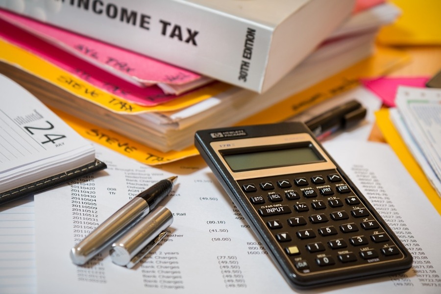 stack of papers with folder labelled income tax, and calculator and pen